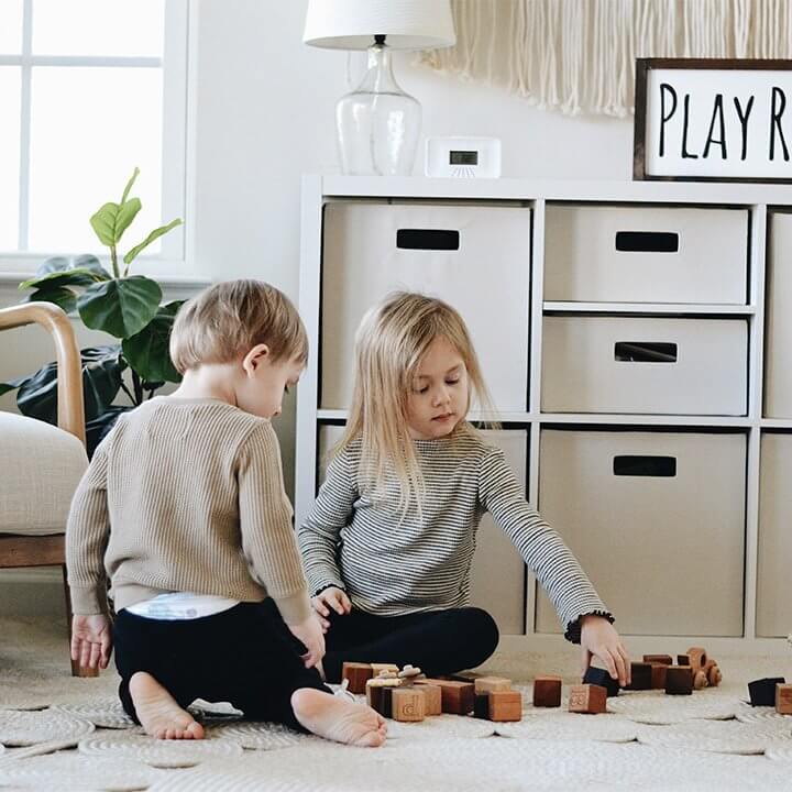A boy and girl play with blocks near a shelf that has a First Alert CO Detector on it.