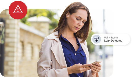 A woman receives a First Alert app notification on her smartphone of a leak detected in her home.