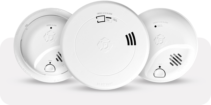 Three white smoke detectors on a light gray background